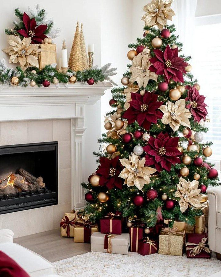 Decorated Christmas tree with red and gold poinsettias standing next to a white fireplace mantel.